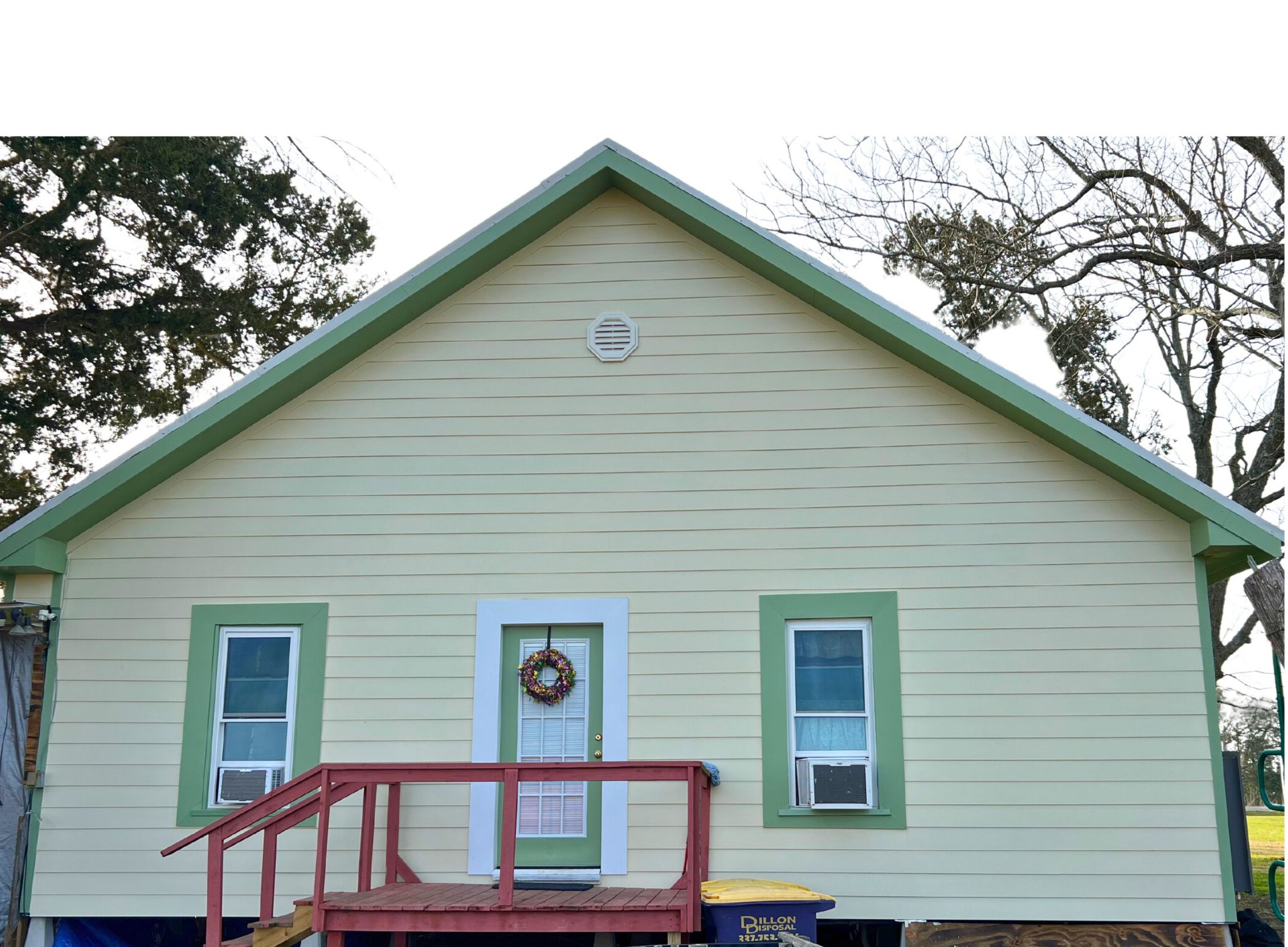 A sage-green house with new vinyl siding and green trim, completed by Deane Construction
